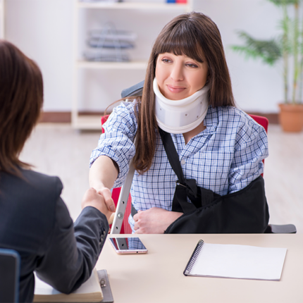 Injured worker with a neck brace and arm sling shakes hands with her lawyer.